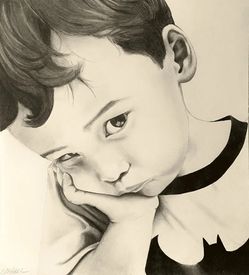 Boy in a Batman shirt resting his chin on his hand